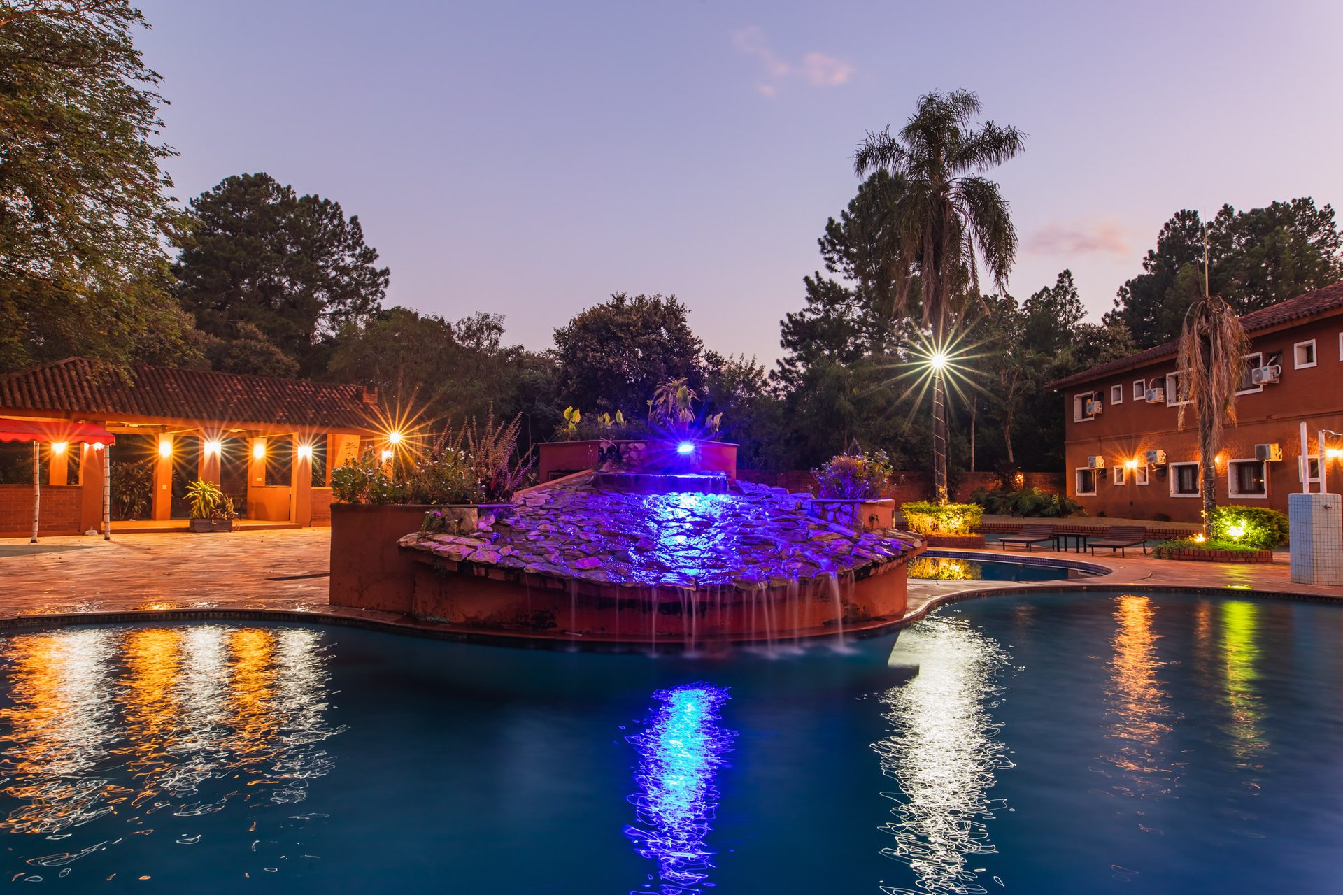 Piscina iluminada por la noche en Marcopolo Suites